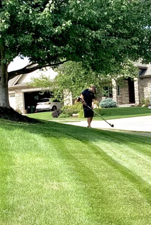 Man weed whacking a green, well maintained lawn