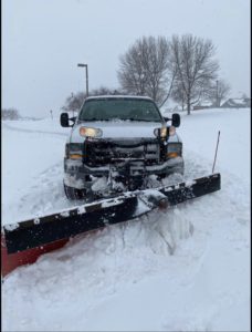 Company snow plowing truck performing snow removal on driveway